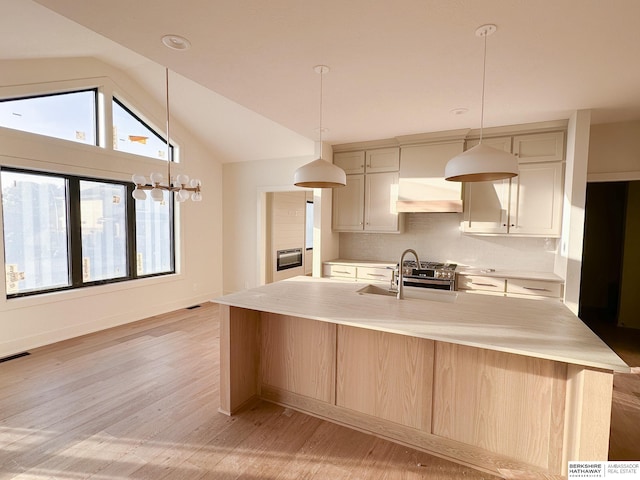 kitchen with lofted ceiling, sink, custom range hood, and a center island with sink