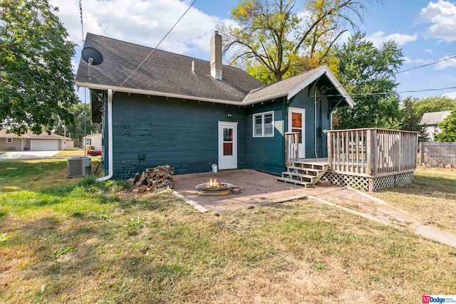 rear view of property with a wooden deck, a garage, a fire pit, central AC, and a lawn