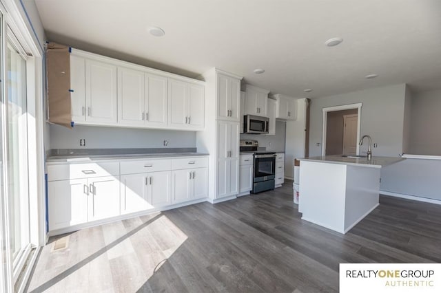 kitchen featuring dark hardwood / wood-style flooring, a kitchen island with sink, stainless steel appliances, and white cabinets