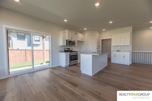 kitchen featuring dark wood finished floors, white cabinets, stainless steel appliances, and a sink