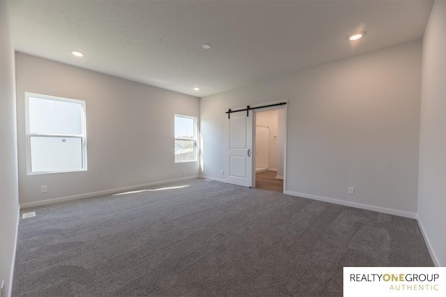 carpeted spare room with a barn door