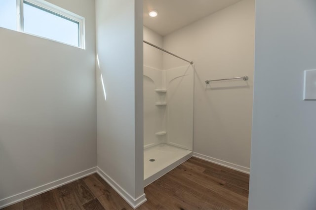 full bathroom featuring baseboards, wood finished floors, and a shower