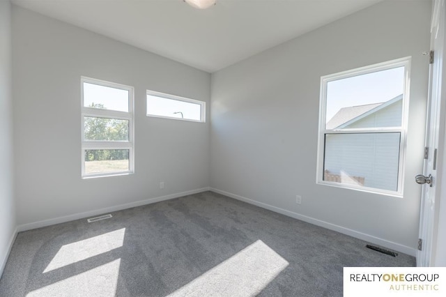 carpeted spare room featuring visible vents and baseboards