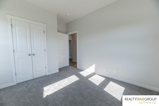 unfurnished bedroom with dark carpet and a closet