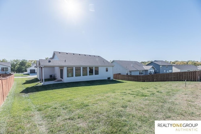 back of house featuring fence, a lawn, and a residential view