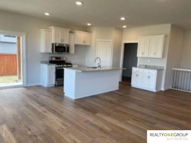 kitchen with a center island with sink, dark hardwood / wood-style floors, appliances with stainless steel finishes, and white cabinetry