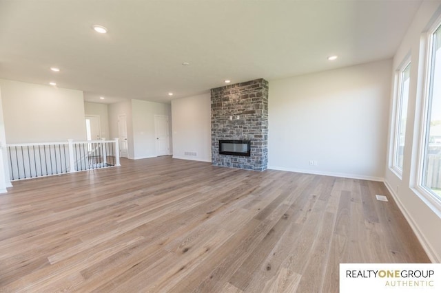 unfurnished living room with visible vents, recessed lighting, light wood finished floors, and a brick fireplace