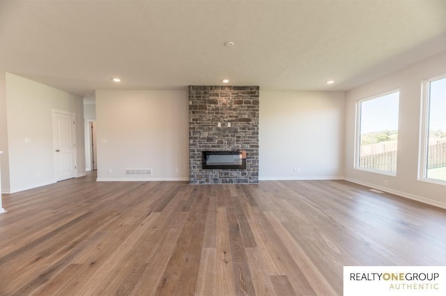 unfurnished living room featuring a large fireplace, wood finished floors, recessed lighting, and visible vents
