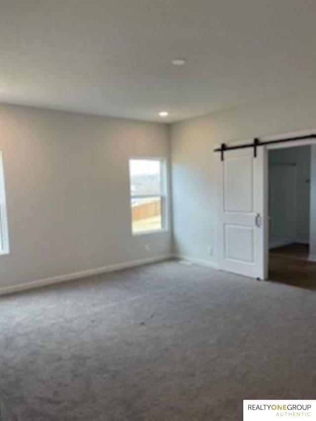 carpeted spare room with a barn door