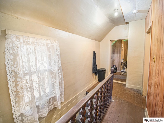 corridor with dark hardwood / wood-style flooring and vaulted ceiling