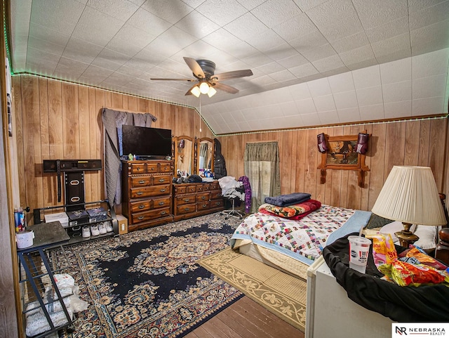 bedroom with lofted ceiling, wooden walls, ceiling fan, and wood-type flooring