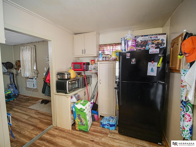 kitchen with cooling unit, white cabinetry, black fridge, and light wood-type flooring