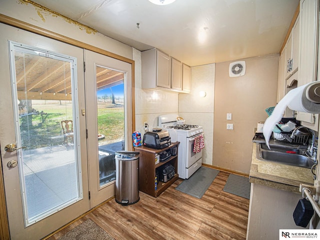 kitchen featuring white cabinets, light hardwood / wood-style flooring, sink, and white gas range oven