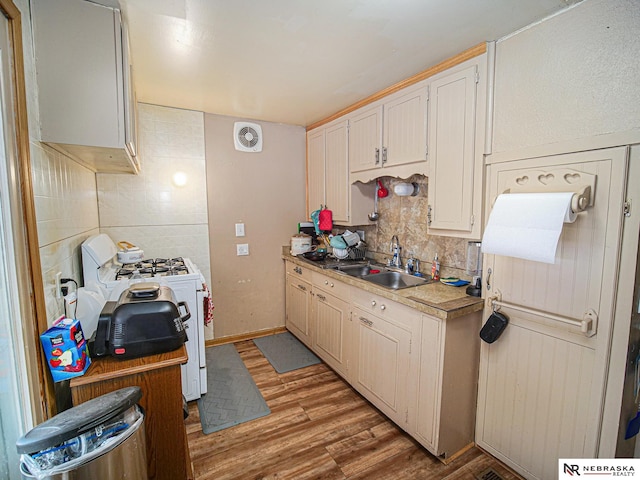 kitchen with white range with gas cooktop, light hardwood / wood-style floors, sink, and tasteful backsplash