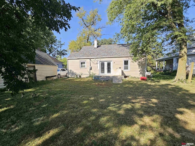 rear view of property featuring french doors and a lawn