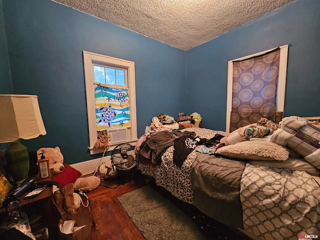 bedroom with cooling unit, hardwood / wood-style floors, and a textured ceiling