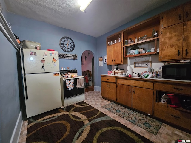 kitchen with light hardwood / wood-style floors, a textured ceiling, and white appliances