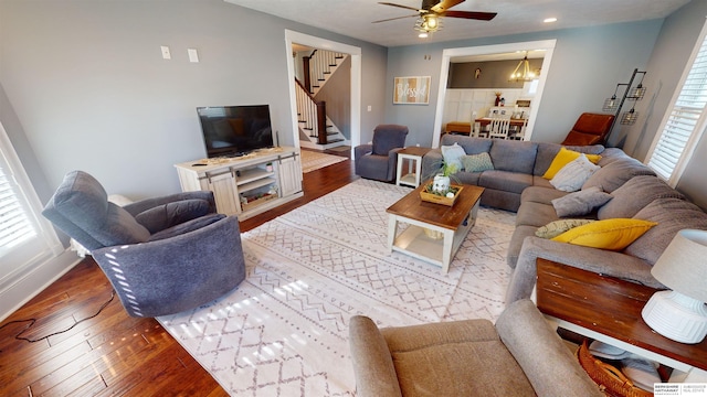 living room with a fireplace, ceiling fan with notable chandelier, and dark hardwood / wood-style floors