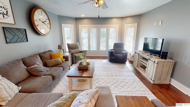 living room with hardwood / wood-style flooring, a textured ceiling, and ceiling fan