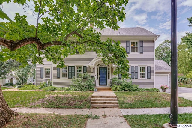 colonial inspired home with a front lawn and a garage