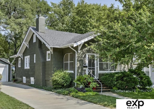 view of front of property featuring an outbuilding, a shingled roof, and a chimney