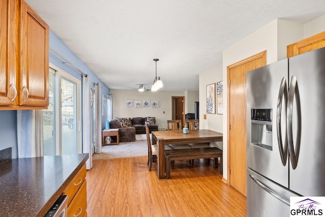 kitchen featuring a textured ceiling, hanging light fixtures, light hardwood / wood-style floors, and stainless steel refrigerator with ice dispenser