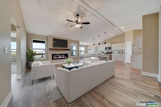 living room with ceiling fan, light hardwood / wood-style flooring, lofted ceiling with beams, and sink