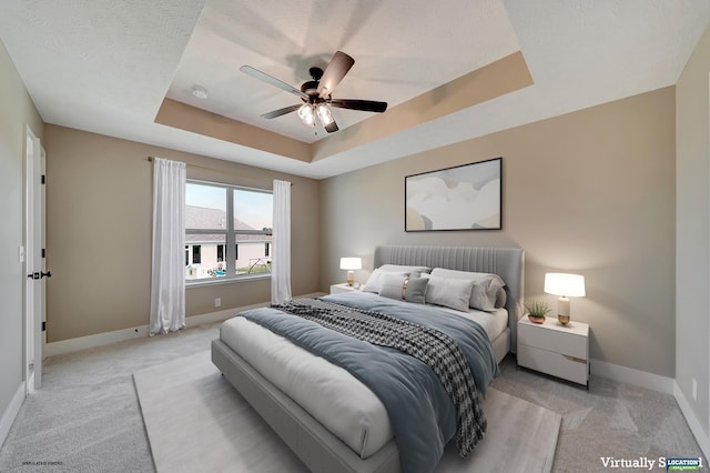 carpeted bedroom featuring a raised ceiling, a textured ceiling, and ceiling fan