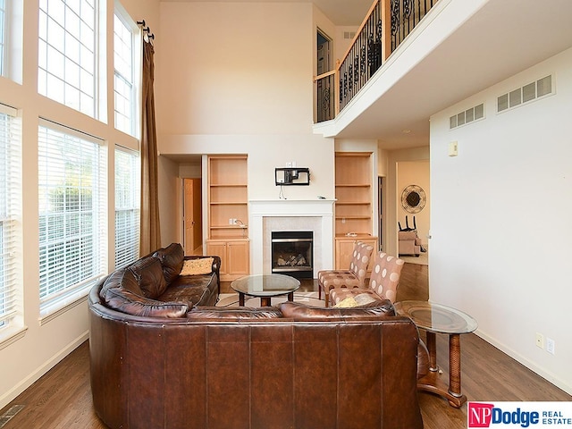 living room featuring a high ceiling, built in features, and dark wood-type flooring