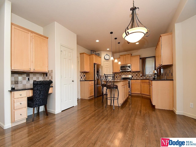 kitchen featuring dark wood-type flooring, appliances with stainless steel finishes, a kitchen bar, and a center island