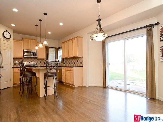 kitchen featuring stainless steel appliances, pendant lighting, dark hardwood / wood-style floors, and light brown cabinets