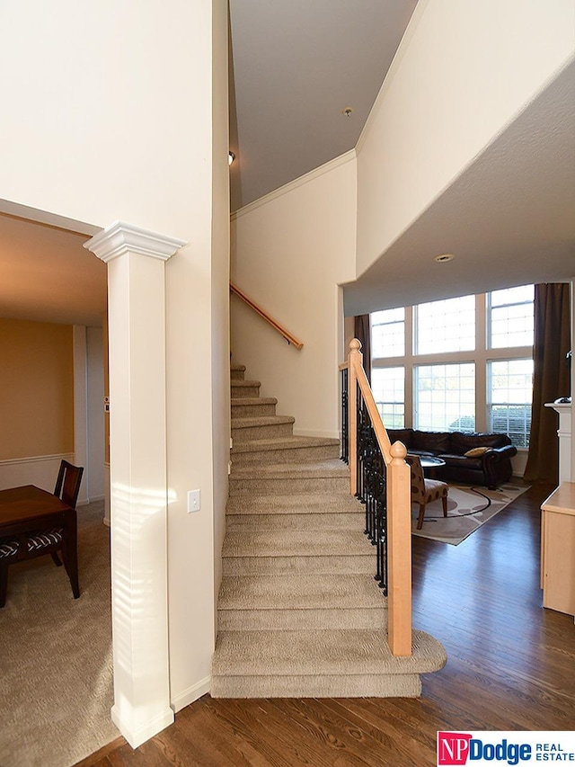 staircase with hardwood / wood-style floors and decorative columns