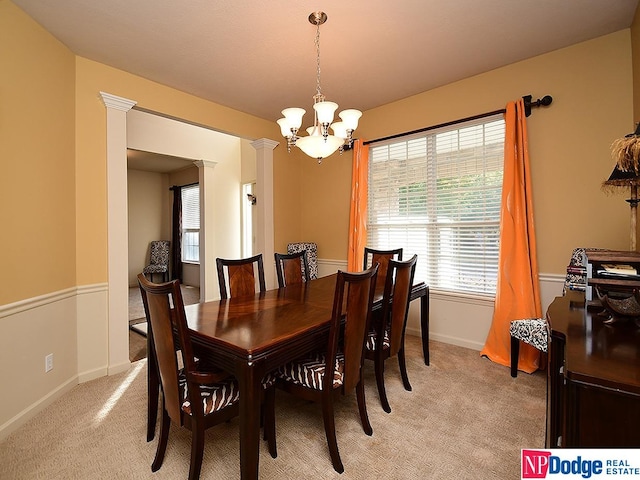 dining area featuring ornate columns, a chandelier, and light colored carpet