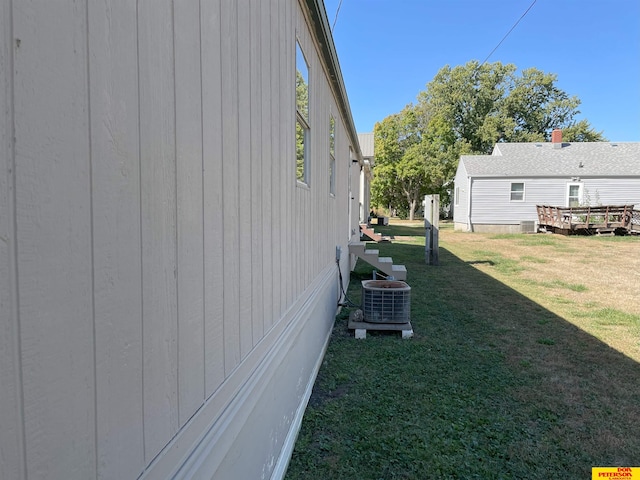 view of side of home featuring cooling unit and a lawn