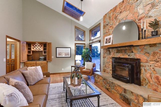 living room with hardwood / wood-style floors, a stone fireplace, and high vaulted ceiling