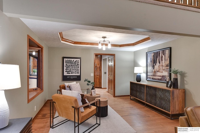 living room featuring an inviting chandelier, light hardwood / wood-style flooring, and a tray ceiling