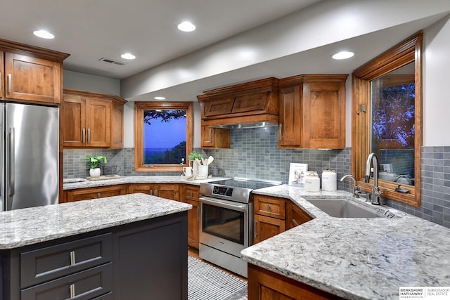 kitchen featuring tasteful backsplash, appliances with stainless steel finishes, custom range hood, sink, and light stone counters