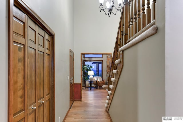 hallway featuring a high ceiling, light hardwood / wood-style flooring, and a notable chandelier