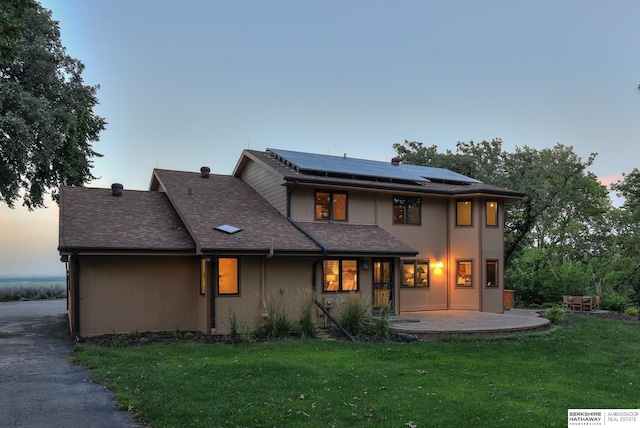 exterior space featuring a patio area, solar panels, and a lawn