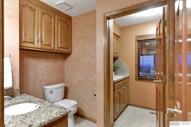 bathroom featuring vanity, toilet, a textured ceiling, and tile patterned flooring