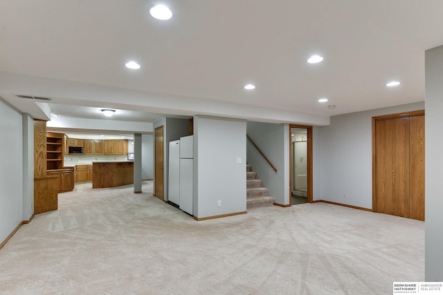 interior space with light carpet, kitchen peninsula, and white refrigerator