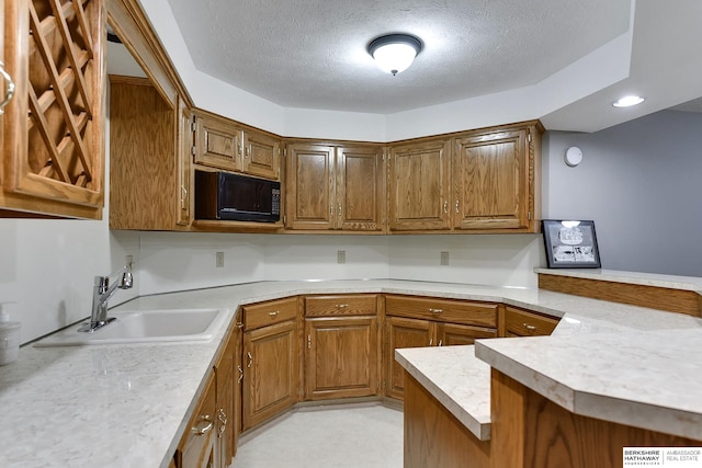 kitchen with kitchen peninsula, a textured ceiling, and sink