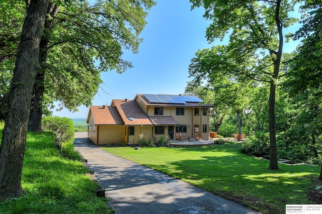 view of front of house featuring a garage, a front lawn, and solar panels