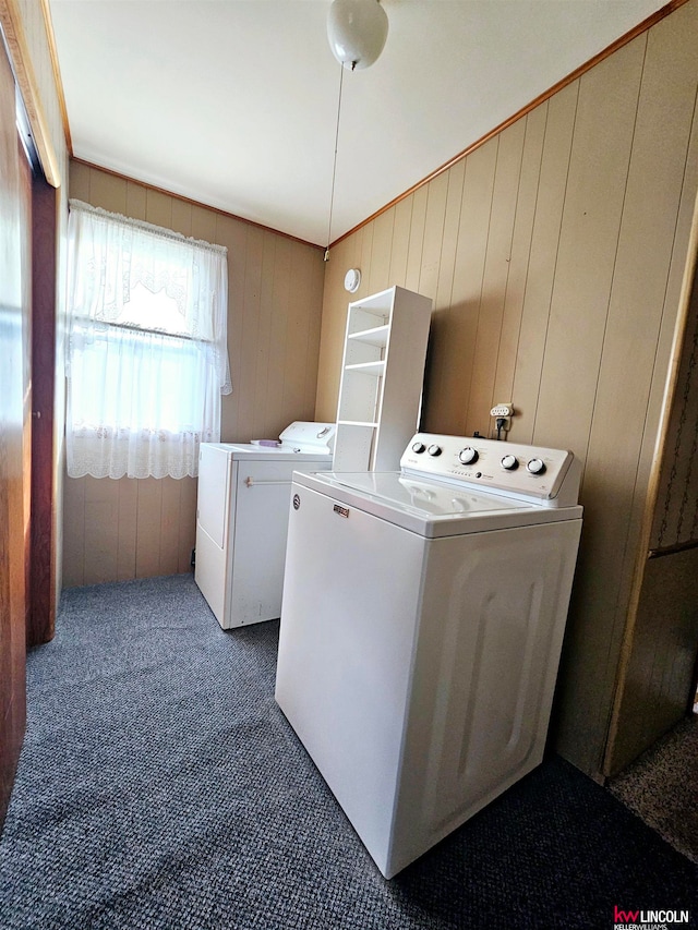 washroom with washing machine and dryer, dark colored carpet, and wooden walls