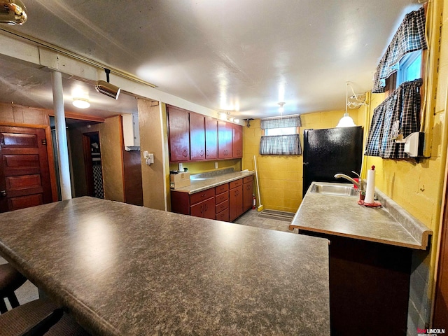 kitchen featuring black fridge, a kitchen breakfast bar, sink, and kitchen peninsula