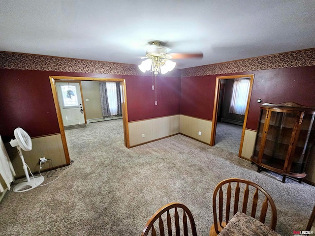 unfurnished dining area featuring ceiling fan, a baseboard radiator, and light carpet