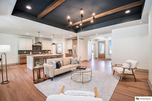 living room with a raised ceiling, light hardwood / wood-style floors, and beamed ceiling