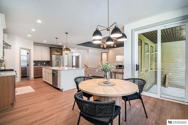 dining space featuring sink, a chandelier, and light hardwood / wood-style flooring