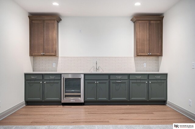 bar with beverage cooler, light hardwood / wood-style flooring, and decorative backsplash