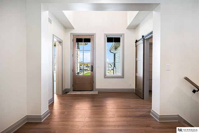 foyer with a barn door and dark hardwood / wood-style flooring